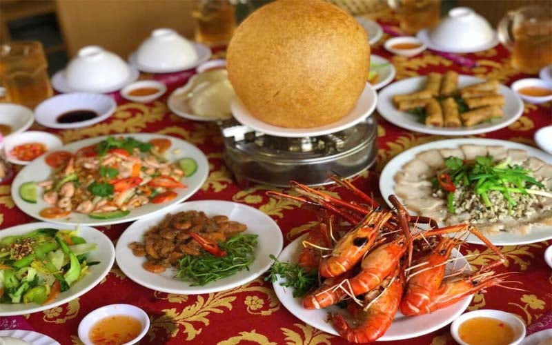A traditional dining table featuring special dishes from the Mekong Delta, like caramelized fish, sour fish soup, and lotus stem salad.